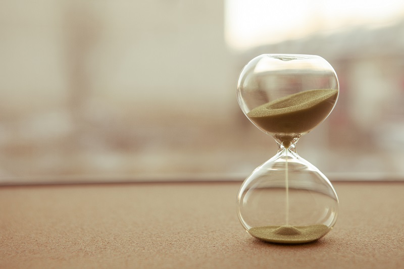 Sand running through the bulbs of an hourglass measuring the passing time in a countdown to a deadline, on a blur background