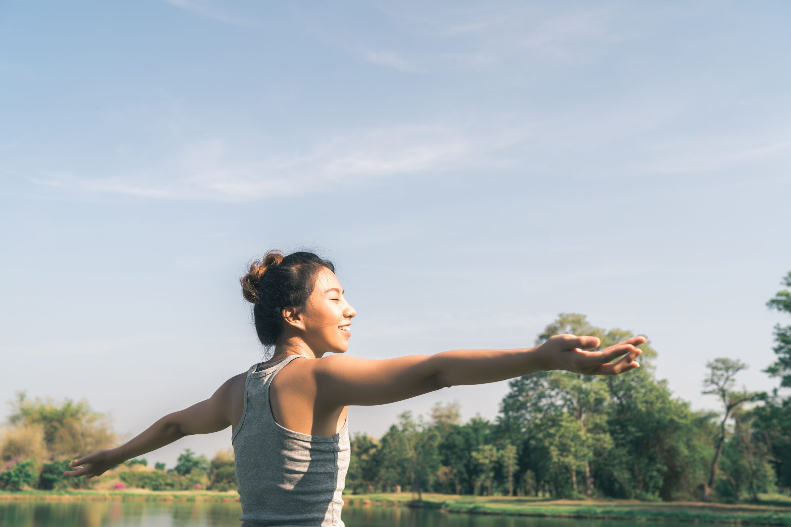 Young asian woman yoga outdoors keep calm and meditates while practicing yoga to explore the inner peace. Yoga have good benefits for health near lake at park. Sport and Healthy lifestyle concept.